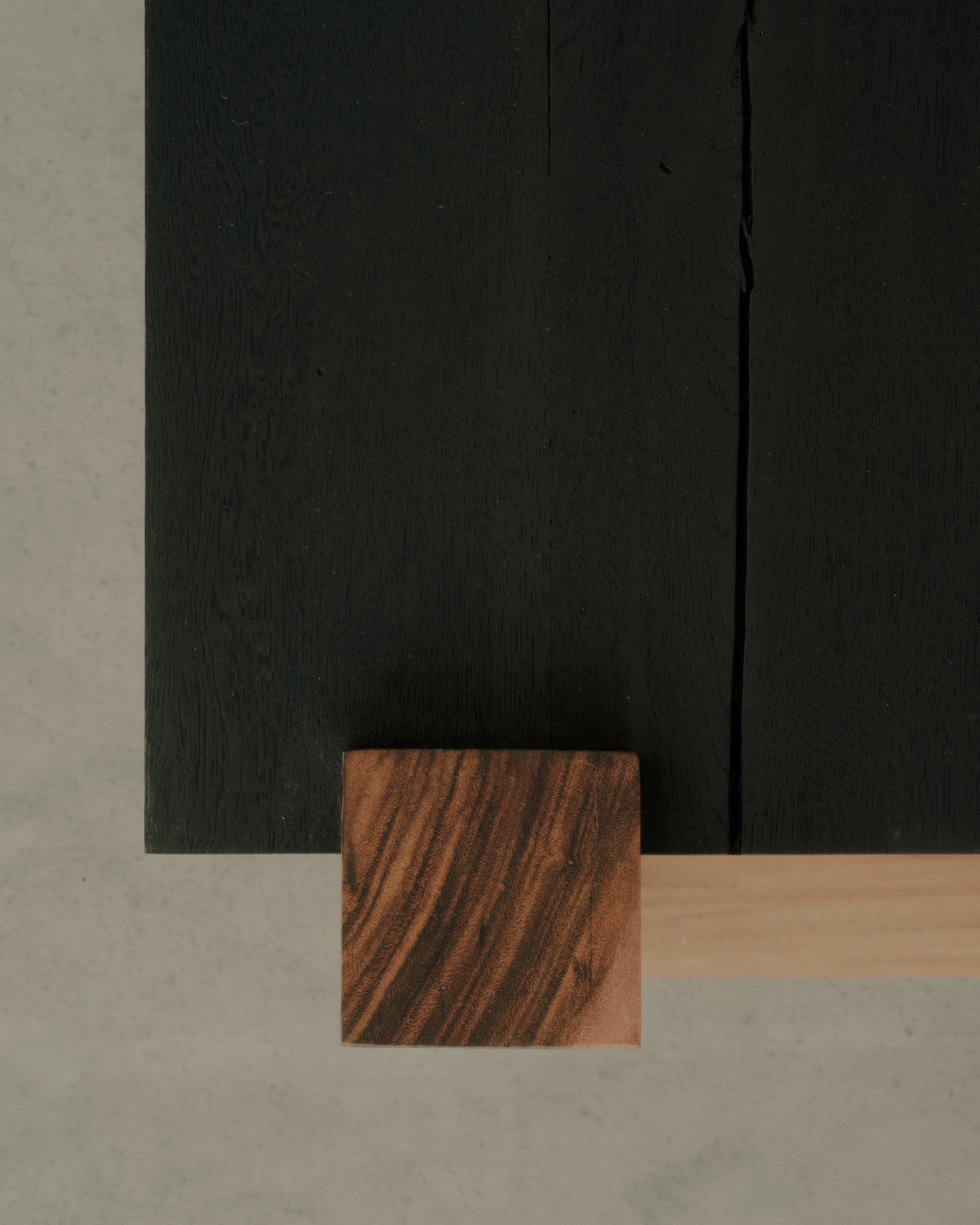 Overhead detail of the desk's blackened top with a mahogany joinery block