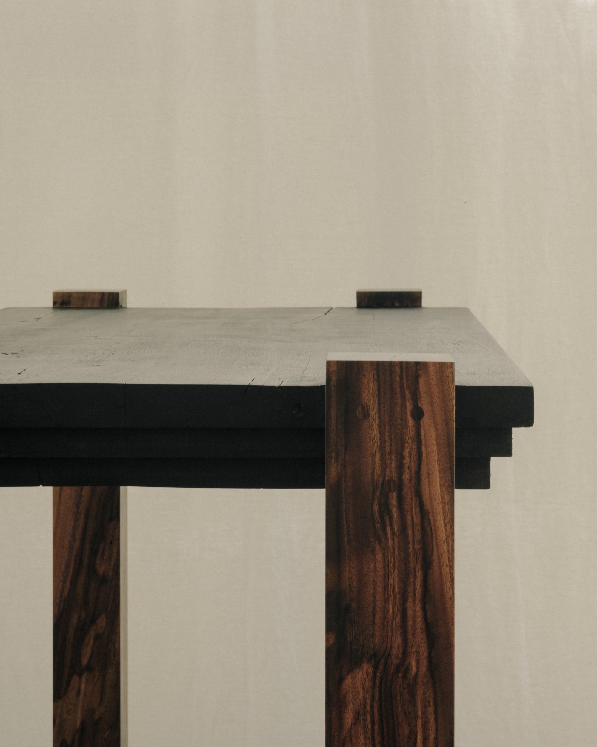 Close-up of the desk's corner joint where the mahogany leg meets the blackened tabletop
